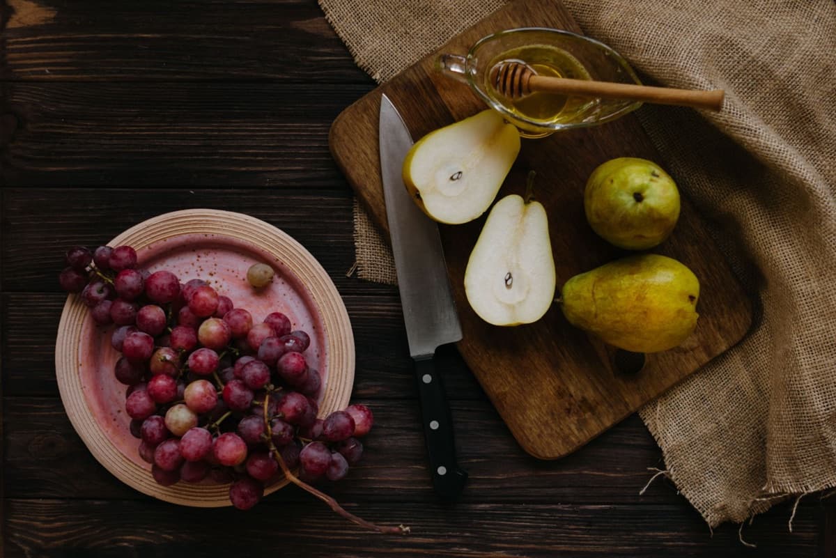 Grapes, sliced pears and honey on a wooden table